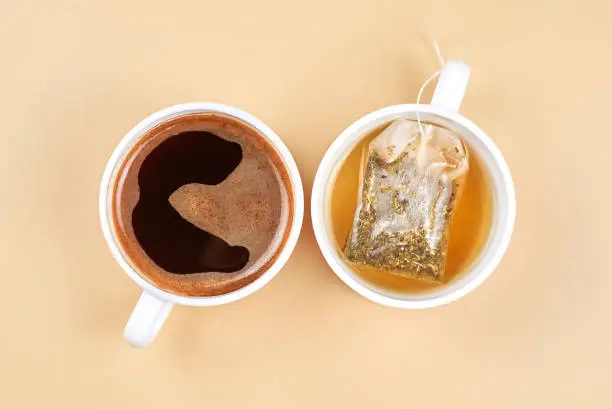 Two cups with coffee and green tea on a beige background.