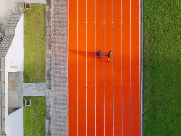 directly above drone point of view asian chinese father son lining up getting ready starting line running at track and run towards finishing line in the morning at track and field stadium beside bleachers - track and field running track sports track beginnings imagens e fotografias de stock