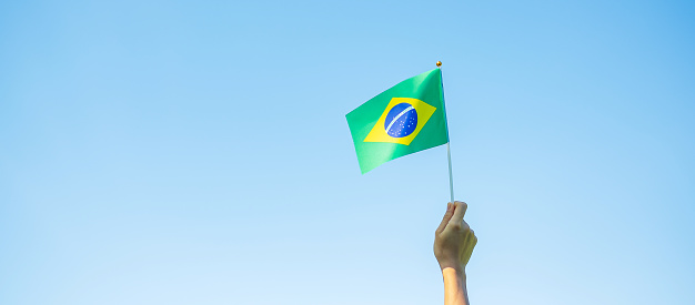 mano sosteniendo la bandera de Brasil sobre fondo azul del cielo. Septiembre Día de la independencia y Conceptos felices de la celebración photo
