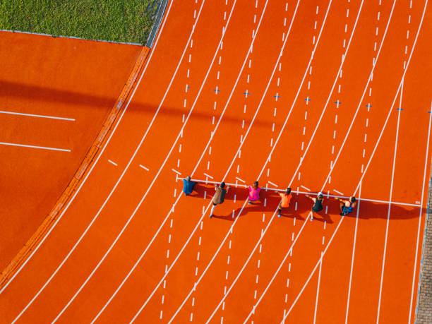 directly above drone point of view Asian chinese athletes lining up getting ready starting line running at track and run towards finishing line in the morning at track and field stadium