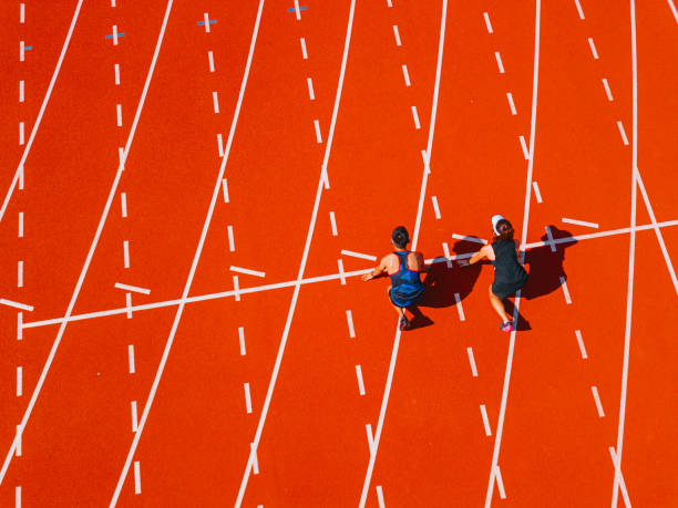 directement au-dessus du point de vue du drone, deux athlètes chinois asiatiques s’alignent pour se préparer à courir sur piste et courir vers la ligne d’arrivée le matin au stade d’athlétisme - championnat de sport photos et images de collection