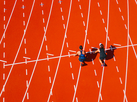 directly above drone point of view Asian chinese athletes lining up getting ready starting line running at track and run towards finishing line in the morning at track and field stadium