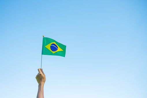 mano sosteniendo la bandera de Brasil sobre fondo azul del cielo. Septiembre Día de la independencia y Conceptos felices de la celebración photo