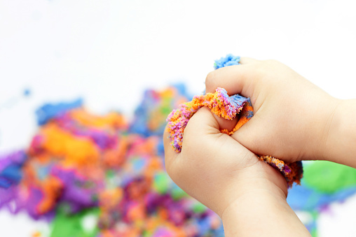 The boy's hands are squeezing bright kinetic sand, children's entertainment.