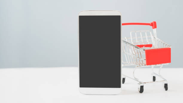 istock white smart phone with clipping path on touchscreen and blurred  empty  shopping cart on dark green background ,online shopping, new normal lifestyle, social distancing concept 1327092651