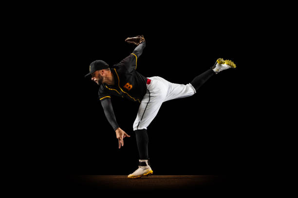 istock Professional baseball player, pitcher in sports uniform and equipment practicing isolated on a black studio background. Team sport concept 1327093338