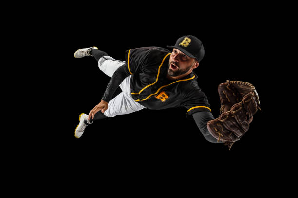 Flying. Baseball player, catcher in sports uniform and equipment practicing isolated on a black studio background. Team sport concept