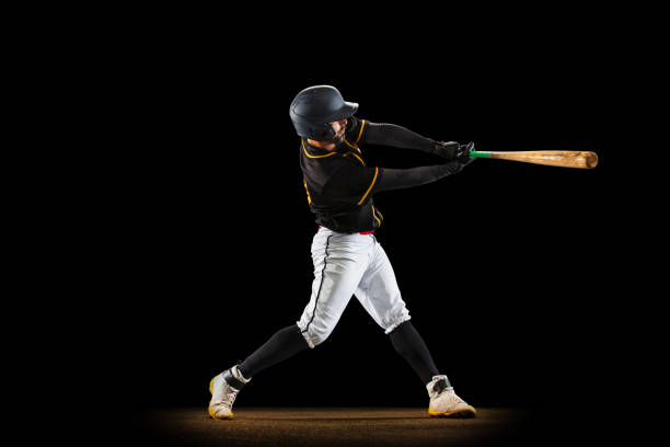 istock Professional baseball player, pitcher in sports uniform and equipment playing baseball isolated on black studio background in neon light. Team sport concept 1327093373