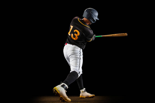 istock Professional baseball player, pitcher in sports uniform and equipment playing baseball isolated on black studio background in neon light. Rear view 1327093375