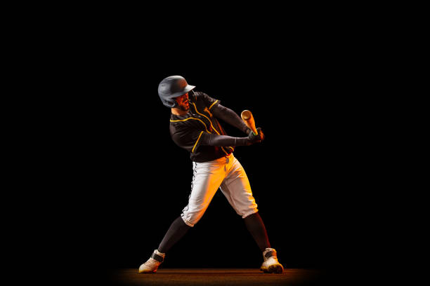 istock Professional baseball player, pitcher in sports uniform and equipment playing baseball isolated on black studio background in neon light. Team sport concept 1327093380