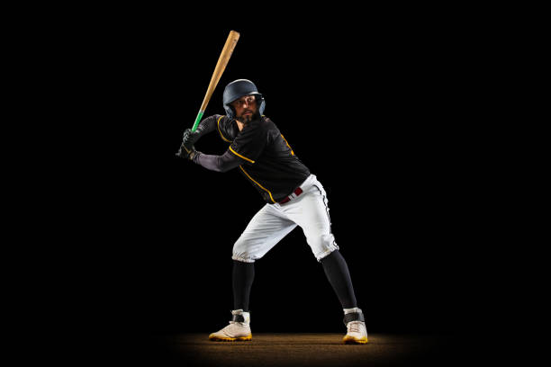 istock Professional baseball player, pitcher in sports uniform and equipment practicing isolated on a black studio background. Team sport concept 1327093385