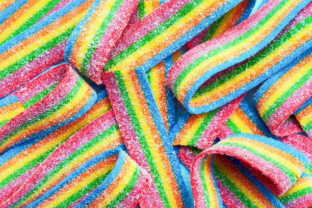 bunte geleebonbons in zuckerstreuseln. sauer aromatisiert regenbogen süßigkeiten hintergrund - kuchen und süßwaren fotos stock-fotos und bilder