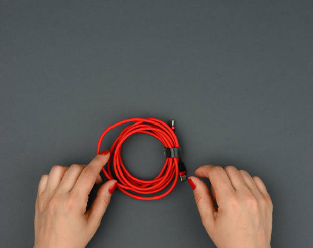 istock female hand holds twisted cable for charging mobile devices in a red textile wrapper on a black background 1327098538
