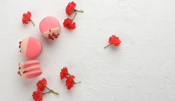 baked red strawberry macarons and rosebuds on a white table, gourmet almond flour dessert, close up baked red strawberry macarons and rosebuds on a white table, gourmet almond flour dessert, top view bud candy stock pictures, royalty-free photos & images