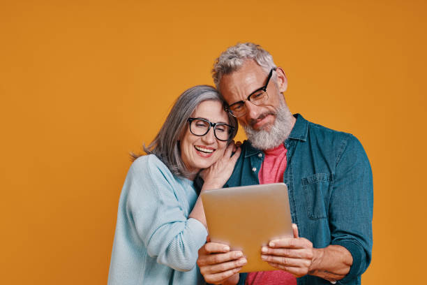 Happy senior couple smiling and using digital tablet and smiling