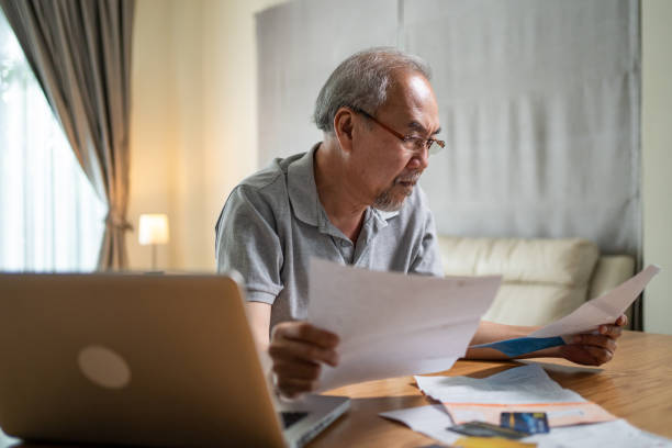 istock Depressed Asian Senior Elderly male feel worry about financial problem. Stressed desperate older man looking frustrated to paperwork and bills think of money debt, budget loss, bankruptcy at home. 1327099256
