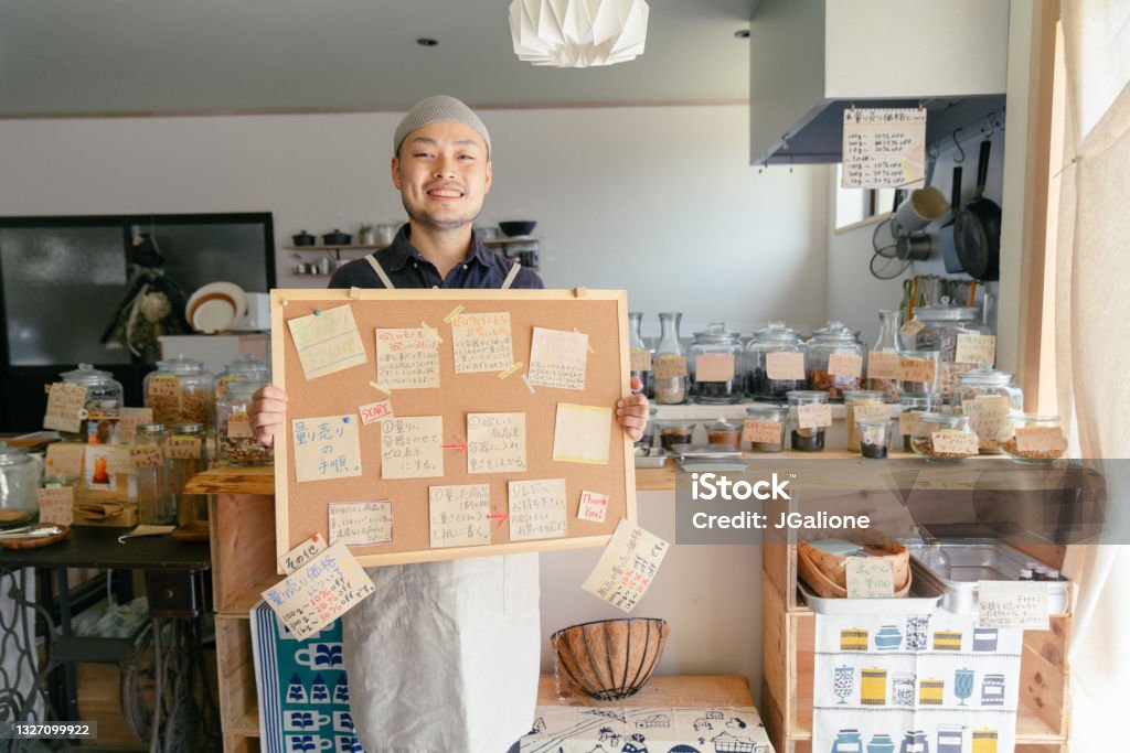 店の仕組みを説明するボードを持つゼロ廃棄物店のオーナー - 日本人のロイヤリティフリーストックフォト