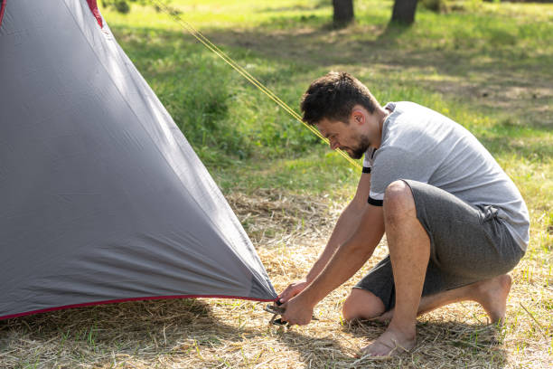 istock A man outdoors in the process of setting up a tent. 1327100572