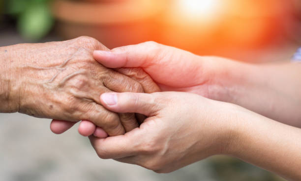 badante, mano badante che tiene mano all'anziano nelle cure dell'ospizio. gentilezza filantropica al concetto di disabilità. - consoling close up senior adult grandparent foto e immagini stock