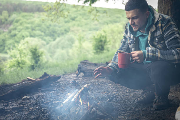 istock A man on a hike sits by the fire and warms himself. 1327103177