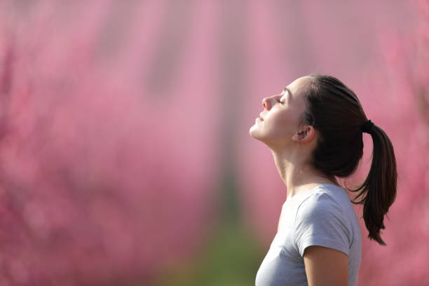 Runner breathing fresh air in a pink field Side view portrait of a runner woman breathing fresh air in a pink field after sport exhaling stock pictures, royalty-free photos & images