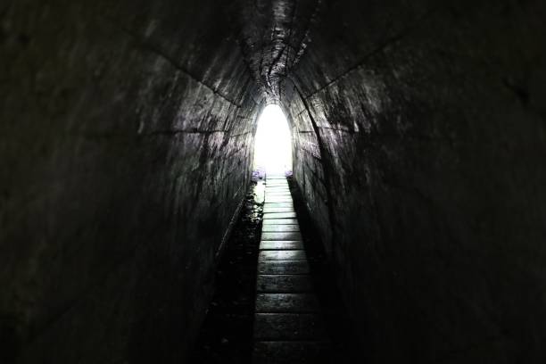 istock Light at the end of the tunnel. Narrow passage and exit. 1327114615