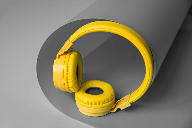istock Yellow wireless headphones on gray creative background. 1327116256