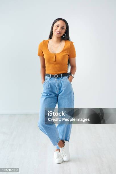 Full Length Portrait Of An Attractive Young Woman Standing With Her Hands In Her Pockets In Studio Stock Photo - Download Image Now