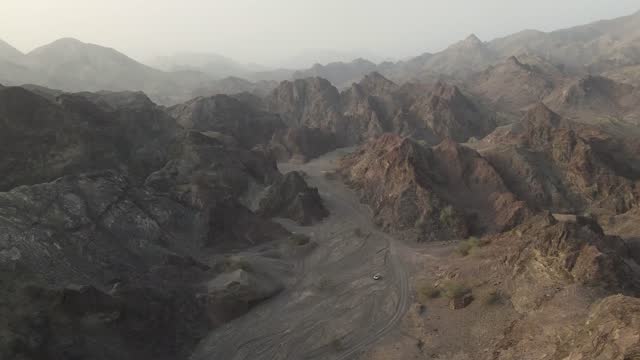 An aerial slow cinematic 4k video over the Hajar Mountains in the UAE showing red and brown rugged mountains