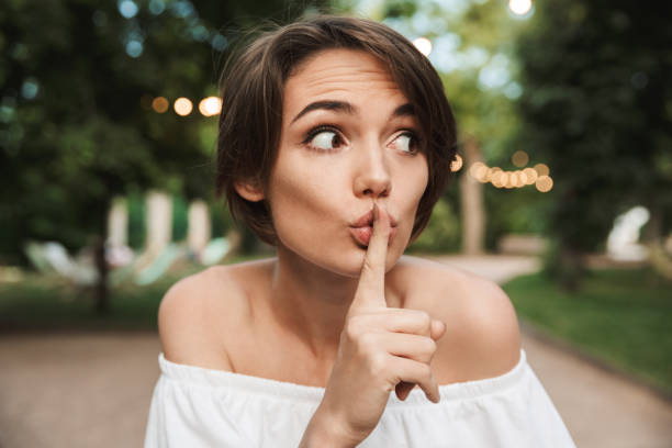 close up of a worried young girl looking away - silence finger on lips businesswoman one person imagens e fotografias de stock