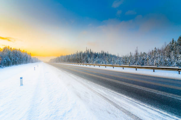 istock Sunrise on a clear winter morning, an empty country road to snowfall passing through a coniferous forest. 1327124021