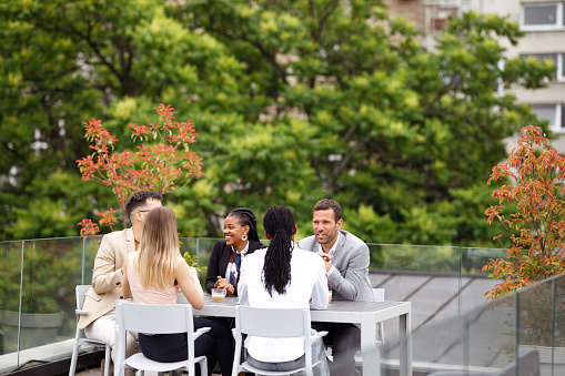 A diverse group of businesspeople is having a meeting in an outdoor restaurant.