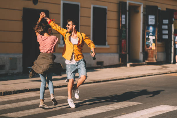 若いカップルが通りで踊り、ビールのボトルを持っている ストックフォト