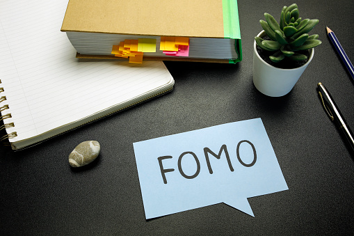 FOMO (fear of missing out) written on paper speech bubble on black table