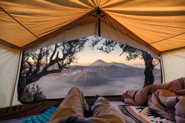 Traveler man relaxing and taking the view of Bromo active volcano inside a tent in the morning at Bromo Tengger Semeru national park, Indonesia