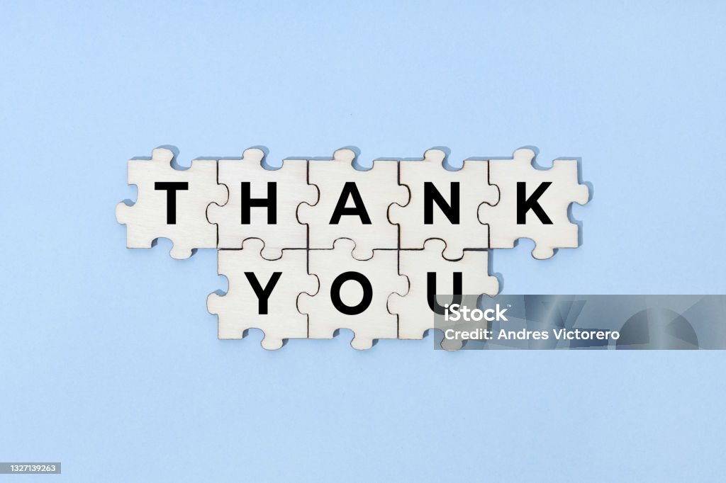Thank you phrase on wooden puzzle pieces Thank you phrase on wooden puzzle pieces isolated on blue background. Top view Thank You - Phrase Stock Photo