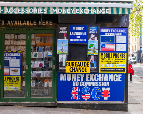 A money exchange kiosk off Charing Cross Road in central London. A display of face coverings can be seen on the door during the COVID-19 pandemic. (Incidental people.)