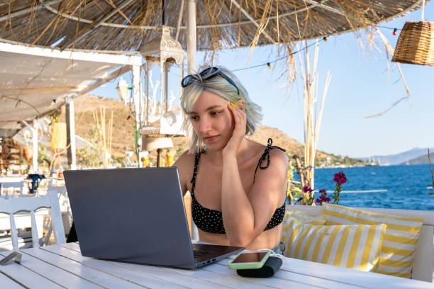 istock blue haired woman working on vacation and using laptop 1327147308