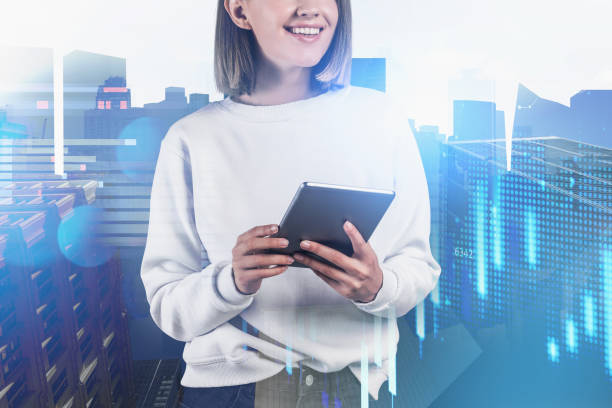 istock Smiling female trader is standing and holding a tablet 1327148001