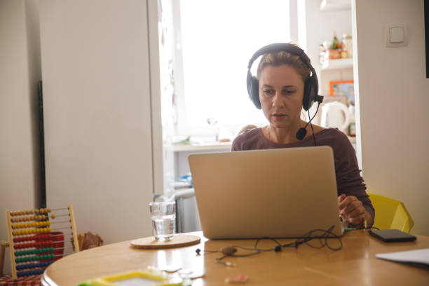 istock Woman sitting at table, attending a work video conference 1327148027