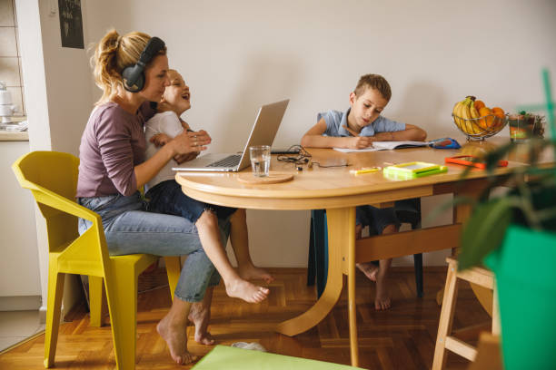 自宅で仕事をしている間、彼女のいたずらな息子を落ち着かせようとしている母 - inconvenience meeting business distracted ストックフォトと画像