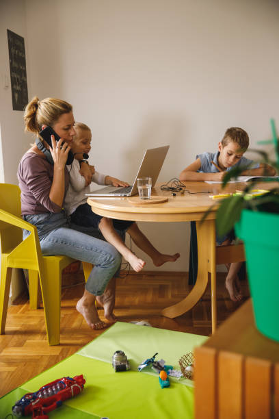 自宅で働く母親が電話会議をしようとして、息子に中断される - inconvenience meeting business distracted ストックフォトと画像
