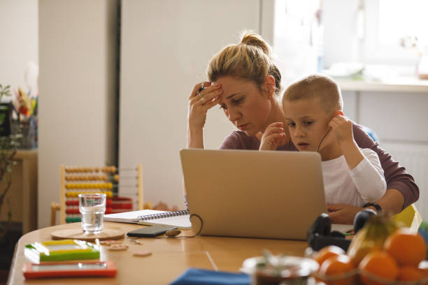 istock Little boy playing with her mother's laptop and headphones while she is working 1327148061
