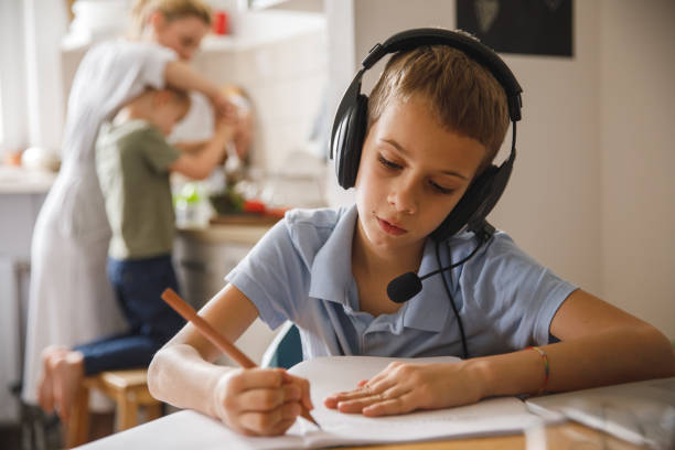 istock Little boy sitting at table and writing homework 1327148820