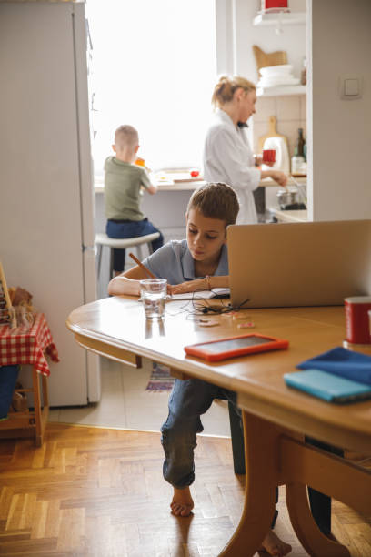 istock Little boy writing homework while his mother and brother are making breakfast 1327148822