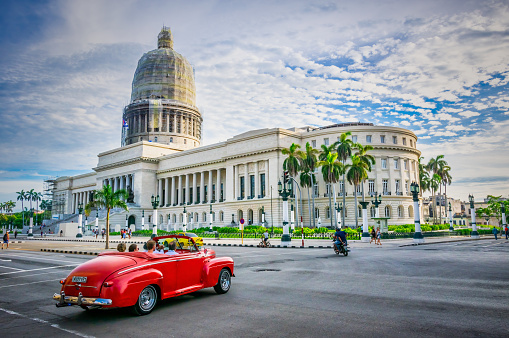 July 31, 2018 - La Havana, Cuba: red convertible american classic car full of tourists in Havana in front of Capitolio at sunset