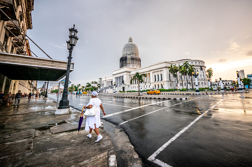 July 31, 2018 - La Havana, Cuba: Senior cuban woman with traditional white dress crossing the street in front of Capitolio, Havana, Cuba