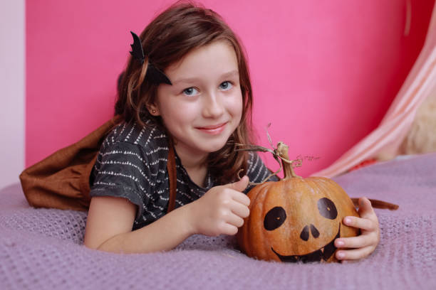 楽しいハロウィンをお過ごし下さい。ピンクの子供の部屋でカボチャを彫っているかわいい女の子。ハロウィーンの準備をする幸せな家族 - six animals audio ストックフォトと画像