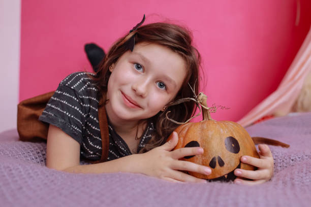 楽しいハロウィンをお過ごし下さい。ピンクの子供の部屋でカボチャを彫っているかわいい女の子。ハロウィーンの準備をする幸せな家族 - six animals audio ストックフォトと画像