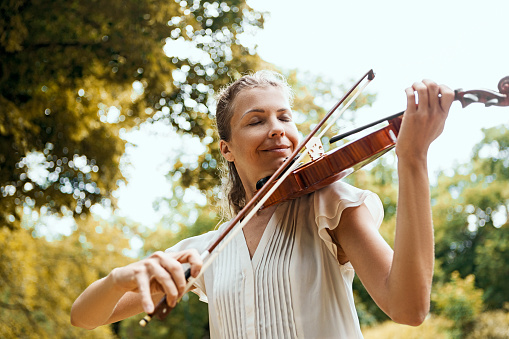 Young woman playing the violin outdoors